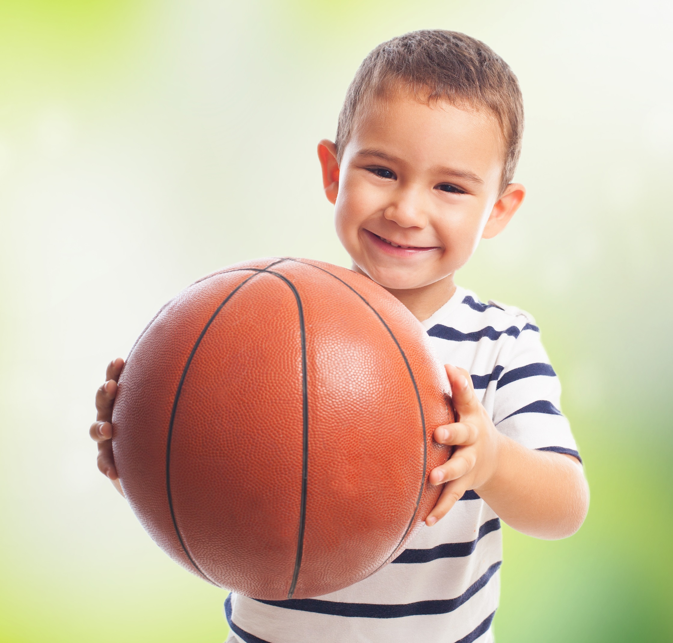 portrait of a little boy holding a basket ball