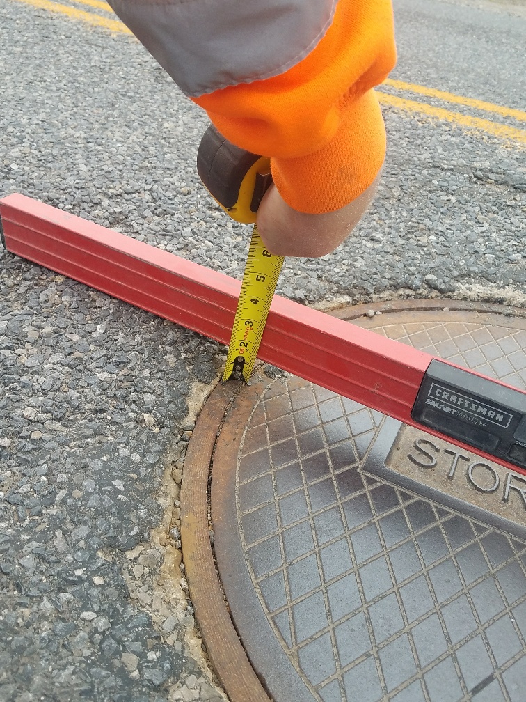 Worker measuring manhole cover